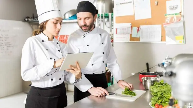 Restaurant cost management software. two chefs reviewing food cost